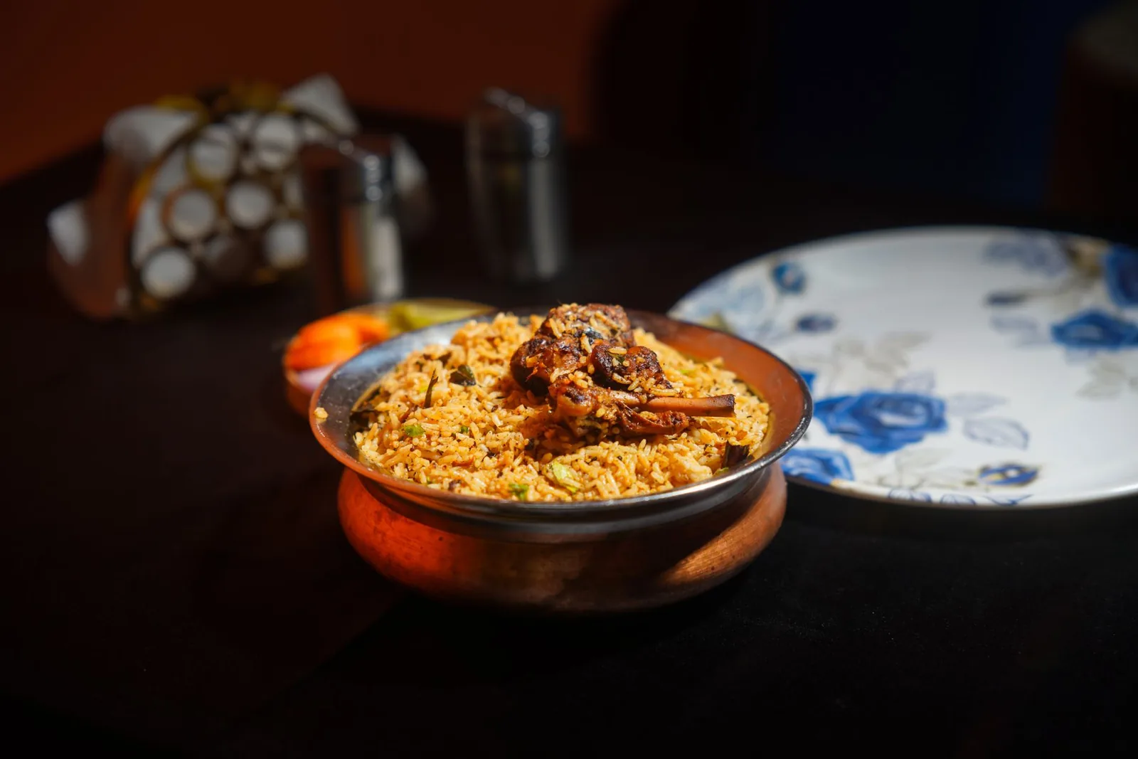 Lucknowi biryani served in a traditional copper bowl
